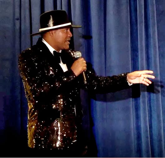 Kevin T. Robertson speaking on stage in a signature black jacket